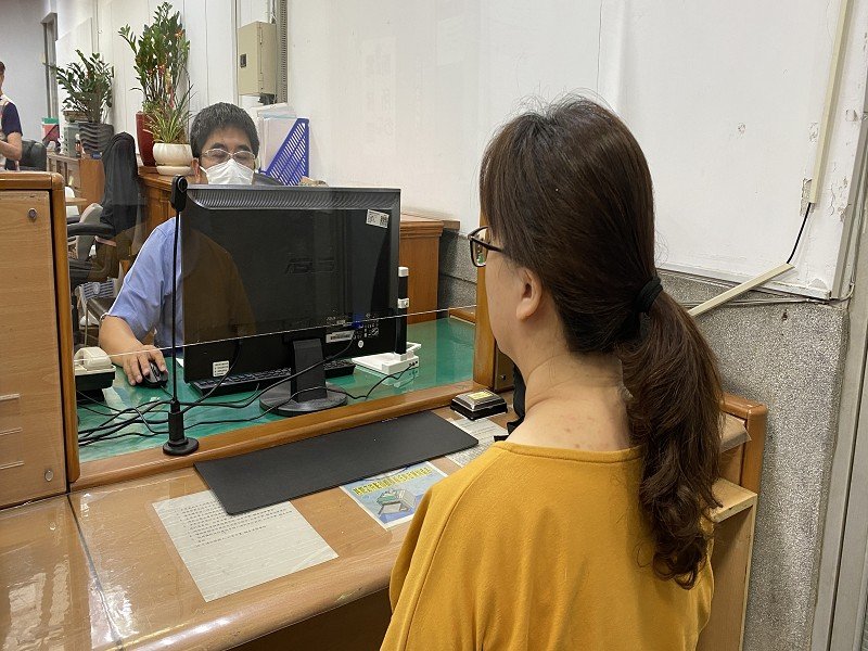地政事務所同仁操作機器與民眾接受拍攝畫面